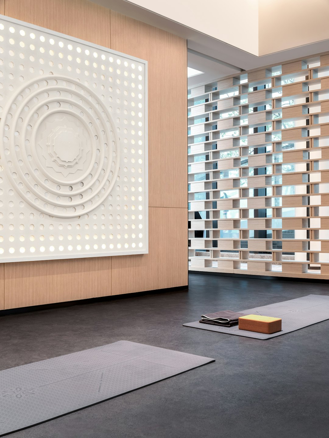 Zwei graue Yogamatten liegen auf dem Boden eines Studios.