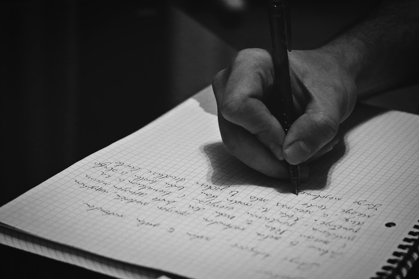 Mit einem dunklen Stift handschriftlich Notizen in ein Notizbuch schreiben.