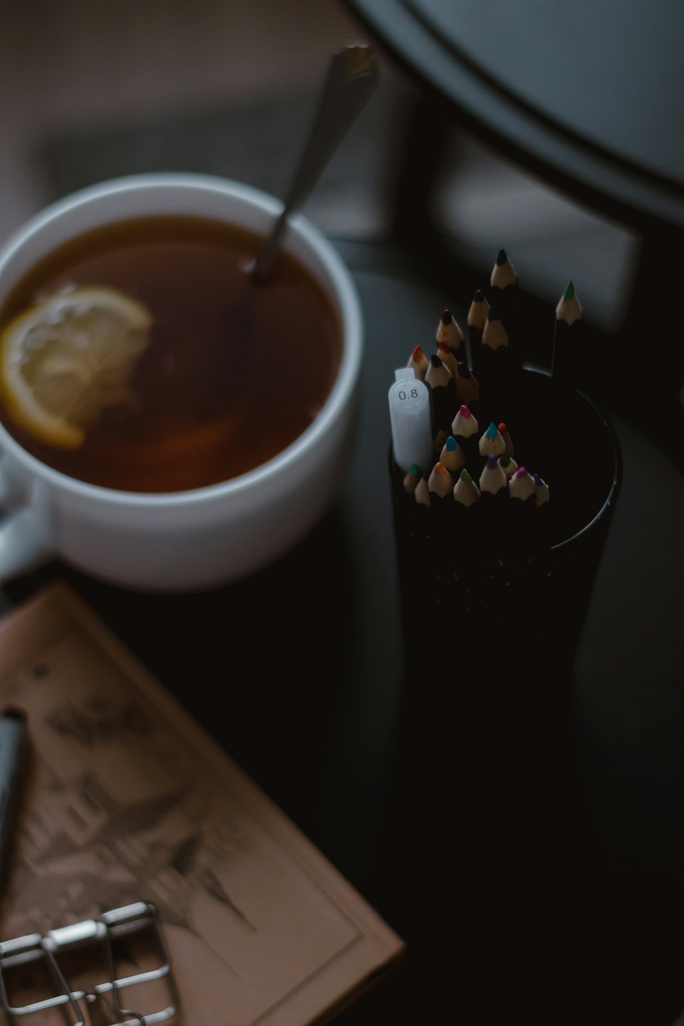 Teetasse und Stiftebehälter auf einem Schreibtisch.