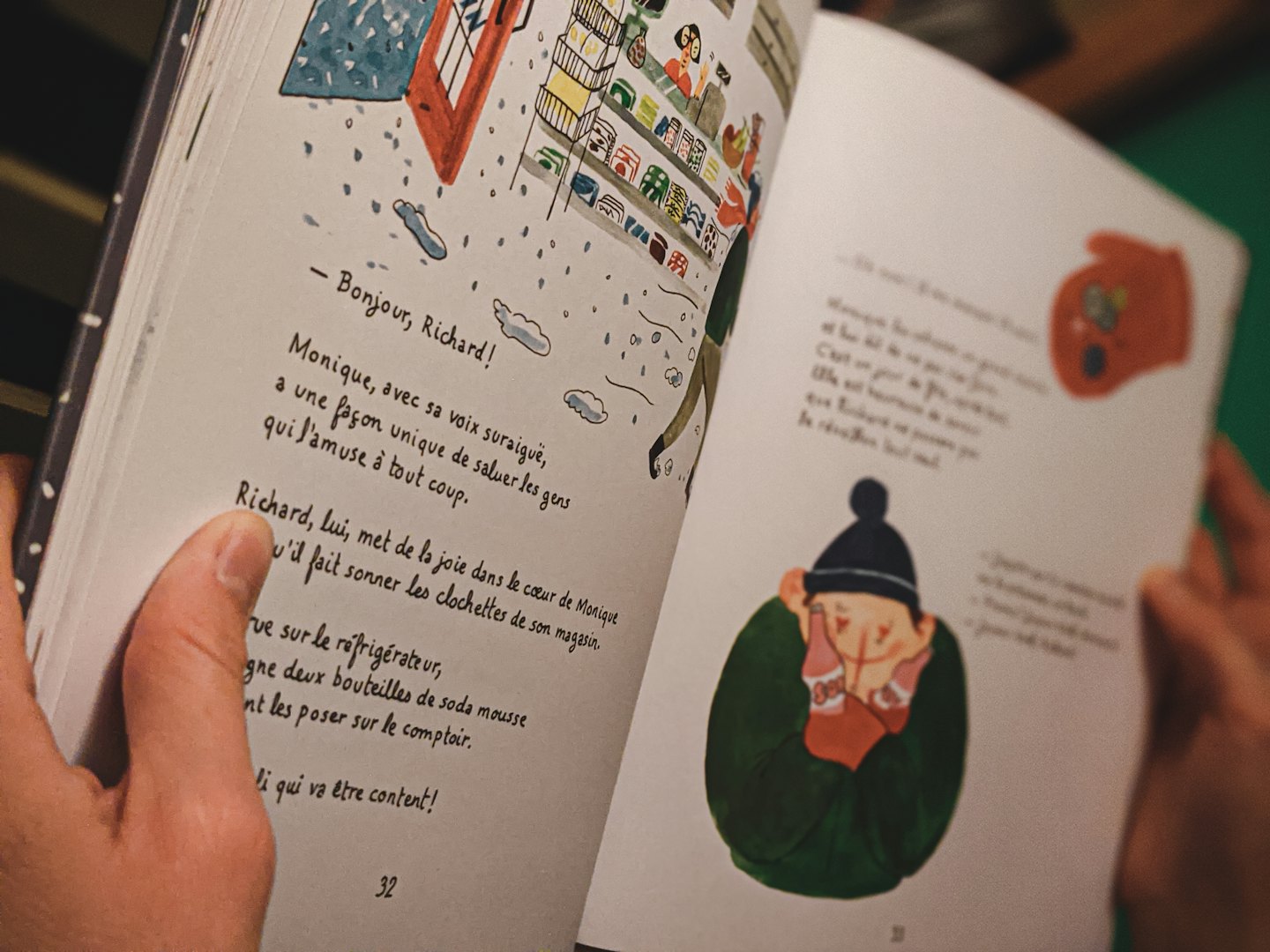 Hände halten ein aufgeschlagenes Kinderbuch mit französischem Text.