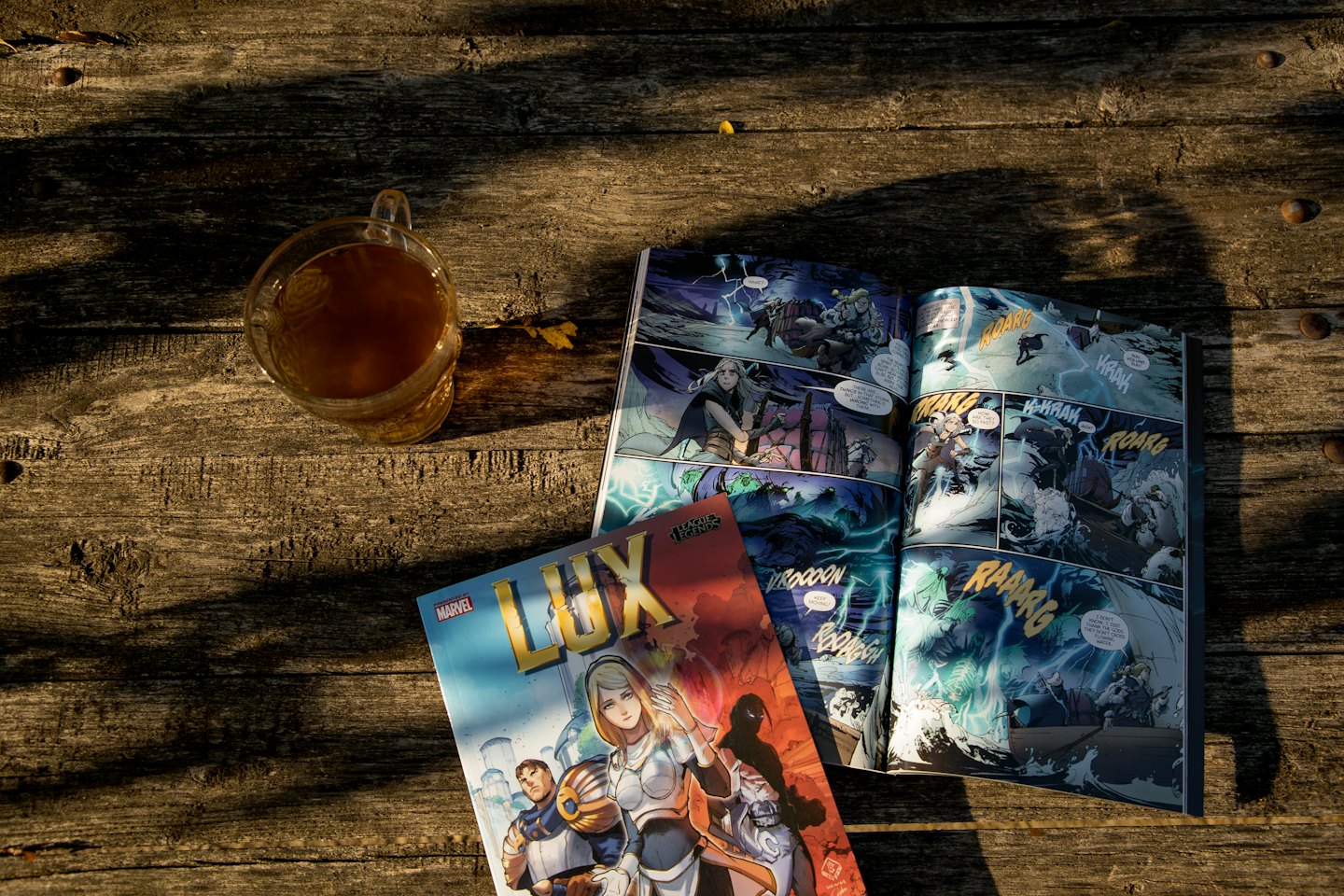 Zwei Comichefte und eine Tasse Tee auf einem Holztisch.